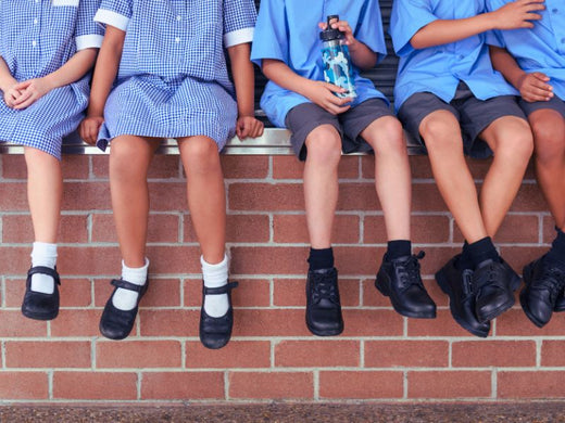 School kids sitting on a brick fence