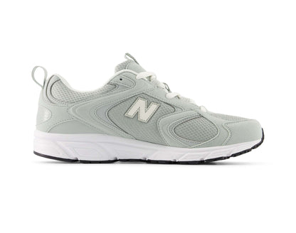 A light sage green New Balance sneaker with white laces, a white midsole, and a black outsole, shown in a side profile on a white background.