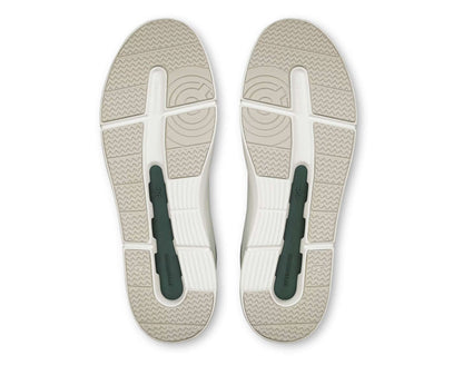 Top view of a pair of sandals with a white sole and green straps on a white background